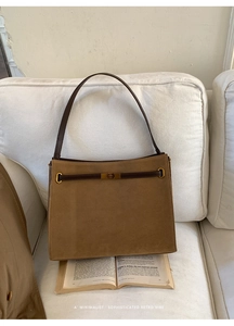 Vue détaillée de la texture daim marron mat et de la boucle en métal doré sur le sac fourre-tout