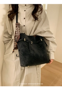 Detail of black suede tote bag with decorative printed silk scarf and metal buckle strap