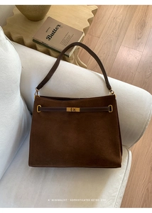 Détail du sac cabas en cuir givré café avec fermoir métallique sur un canapé blanc