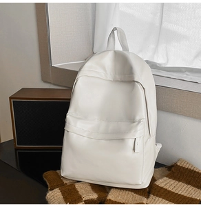 Minimalist white leather travel backpack shown on a textured brown fabric background