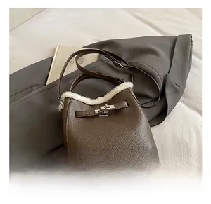 Detail of dark brown pebble leather handbag with white faux fur trim and silver turn-lock