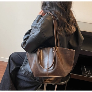 Gros plan sur la texture huilée vintage et les surpiqûres contrastées du sac cabas
