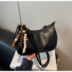 Détail du sac hobo en cuir noir avec perles colorées et longue bandoulière