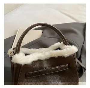 Detail of brown litchi leather bag with white faux fur trim and silver hardware