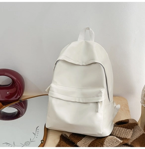 Close-up of minimalist cream backpack with smooth matte finish and zipper detail