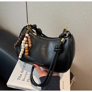 Detail of black matte leather dumpling bag featuring colorful wooden bead tassel decoration