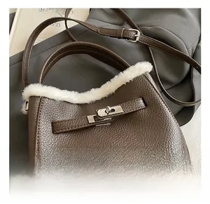 Detail of silver twist lock and white faux fur trim on a brown leather crossbody handbag