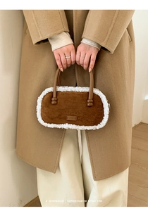 Détail du sac en daim marron avec bordure en laine d'agneau et poignée en cuir