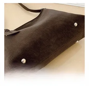 Detailed view of the dark brown tote bag base featuring four silver protective metal studs