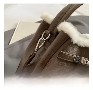 Detailed close-up of dark brown lychee leather bag with white faux fur trim and silver clasp