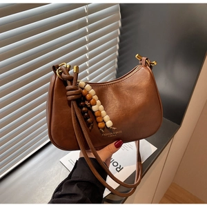 Detail of vintage brown leather bag with wooden bead pendant and gold hardware finish