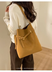Side view of a large vintage caramel bucket bag with strap detail on a female model