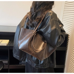 Détail d'un grand sac cabas vintage en cuir marron avec rivets et bandoulières longues
