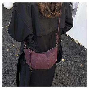 Detail of burgundy faux suede dumpling bag with geometric stitching and knot strap design