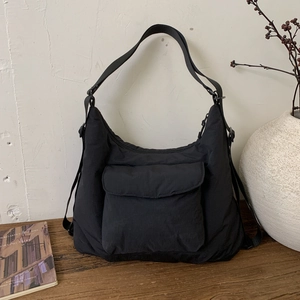 Close-up of minimalist black canvas tote bag showing the flap pocket and adjustable strap