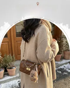 Detail of brown quilted chain mini bag with golden buckle and plush bear charm