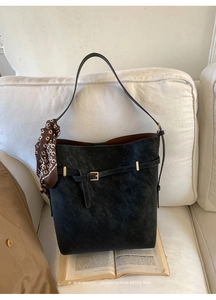 Detail of black tote bag with vintage texture, buckle strap, and patterned silk scarf