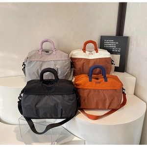 Detail of lightweight nylon travel bags in various colors with reinforced handles