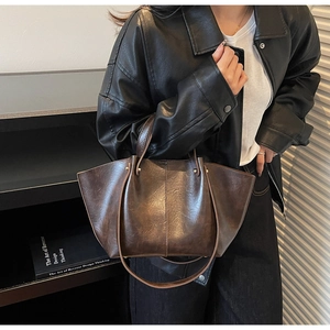 Détail d'un sac cabas marron foncé à ailes avec poignées fines et bandoulière