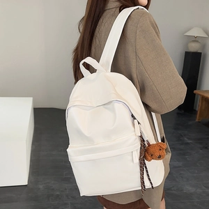 Detail of off-white minimalist travel backpack with cute bear charm and ribbon