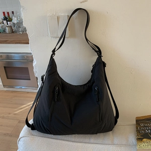 Détail du sac hobo en nylon noir avec deux fermetures éclair verticales et bandoulières