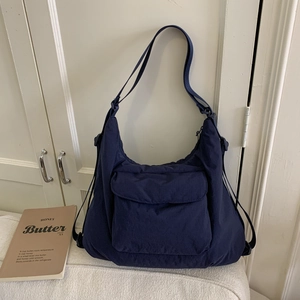 Detail of navy blue hobo bag with front flap pocket and adjustable drawstring accent