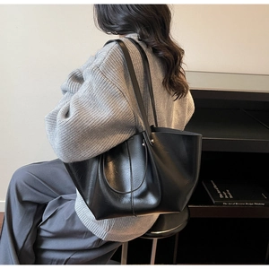 Vue détaillée d'un grand sac cabas noir à texture brillante avec doubles bandoulières