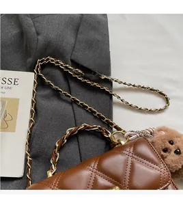 Close-up of brown quilted leather bag with gold chain strap and plush bear charm
