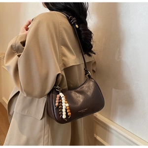 Detail of vintage dark brown faux leather hobo bag with unique beaded tassel charm