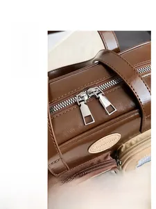 Détail du sac Boston en cuir marron avec fermetures éclair argentées et logo Clutviarot