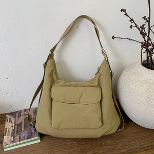 Close-up of khaki nylon tote bag featuring a large front flap pocket and wide strap