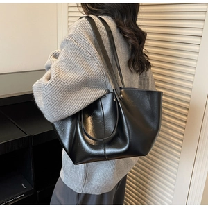 Détail d'un grand sac cabas en similicuir noir montrant la texture lisse et les anses