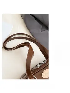 Détail d'un grand sac oreiller en cuir marron avec doubles bretelles et fermeture éclair