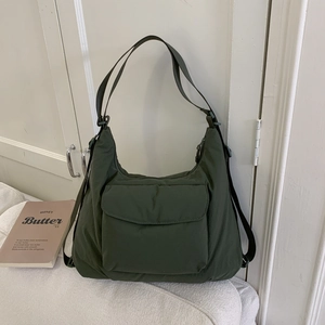 Close-up of olive green nylon tote bag featuring front flap pocket and woven straps