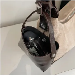 Detail of a dark brown leather hanging pouch with magnetic clasp on a beige tote bag