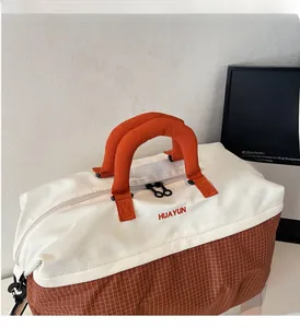 Close-up of contrast color canvas travel bag with thick orange handles and brand logo