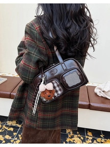 Détail du sac oreiller en cuir marron foncé avec doubles poches et breloque ours