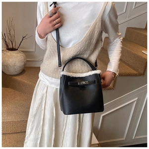 Detail of black lychee leather bucket bag with white faux fur trim and metal swivel lock
