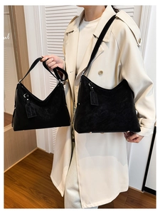Detail view of large and small black leather tote bags with metal feet and logo tag
