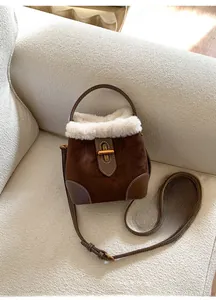 Détail de la bordure en faux mouton et fermoir doré sur le sac seau en daim marron