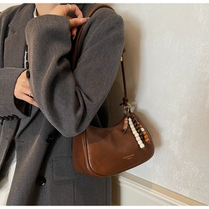 Sac sous le bras rétro en cuir marron avec breloque en perles porté sur un blazer gris