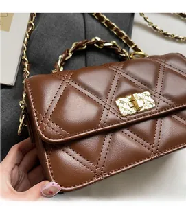 Detail of a brown quilted leather crossbody bag featuring a gold twist lock and metal chain
