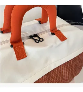 Close-up of the orange top handles and black double zipper on the colorblock tote bag