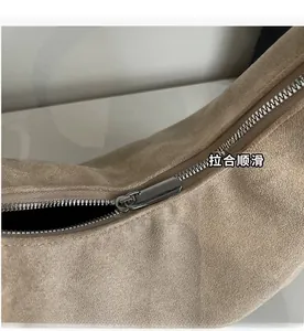 Detail of smooth metal zipper and textured suede fabric on beige dumpling bag