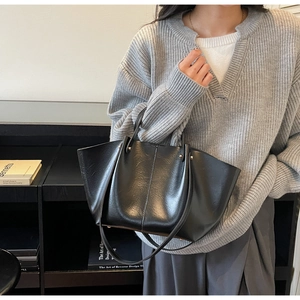 Détail du sac cabas en similicuir noir avec bandoulière réglable et texture cirée à l'huile