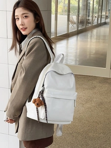 Minimalist large white travel backpack with a cute bear charm shown on a female model