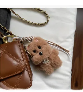 Close-up of a brown plush dog charm with a metal tag on a quilted leather chain bag