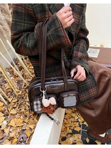 Gros plan du sac bowling marron brillant avec poches en maille et charme d'ours