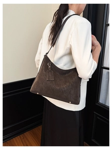 Detail of dark brown suede hobo bag with adjustable strap and silver studs shown on model