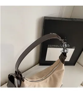 Detail of beige suede dumpling bag with dark brown leather trim and metallic zipper closure